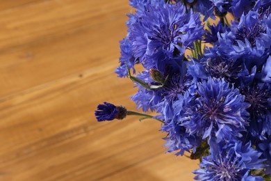 Photo of Beautiful blue cornflowers on wooden table, closeup. Space for text