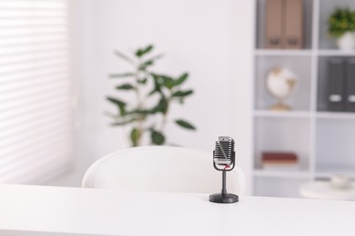 Photo of Microphone on white table indoors, space for text
