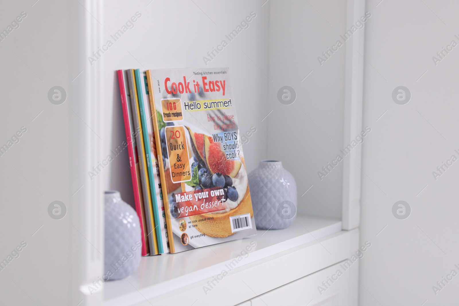 Many different trendy magazines and vases in white shelving unit indoors Photo of Many different trendy magazines and vases in white shelving unit indoors