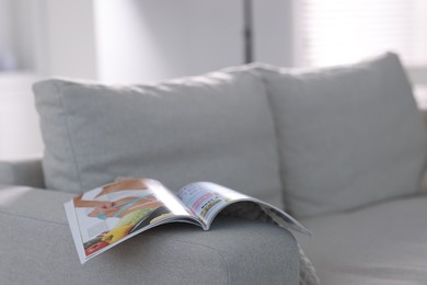 Photo of One trendy magazine on sofa indoors, closeup. Space for text