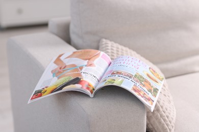 Photo of One trendy magazine on sofa indoors, closeup