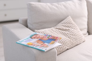 Photo of One trendy magazine on sofa indoors, closeup