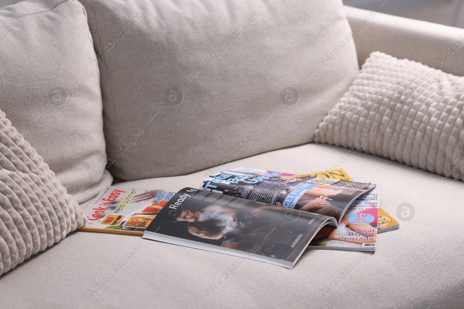 Many different trendy magazines on sofa at home Photo of Many different trendy magazines on sofa at home