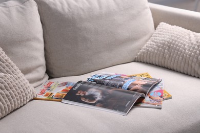 Photo of Many different trendy magazines on sofa at home