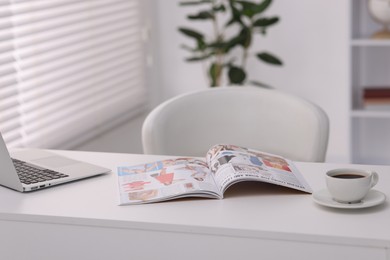 Photo of Open trendy magazine, laptop and coffee on white table indoors
