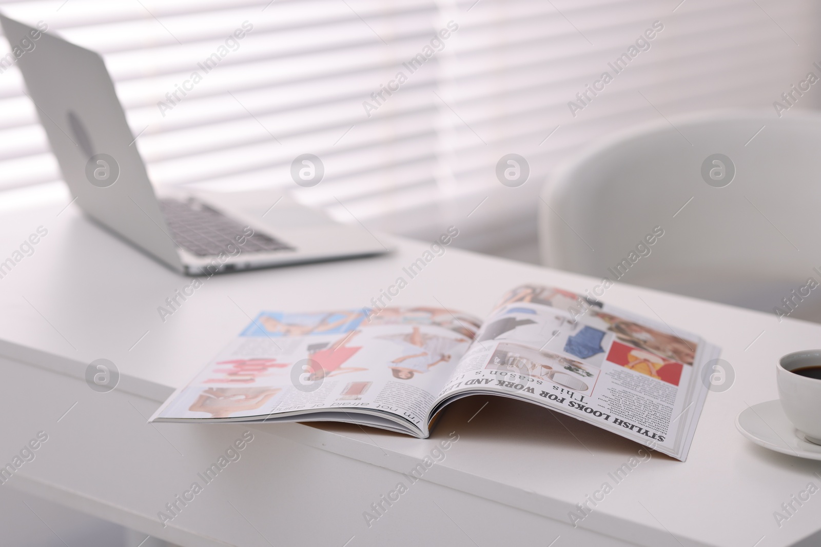 Open trendy magazine, laptop and coffee on white table indoors, closeup Photo of Open trendy magazine, laptop and coffee on white table indoors, closeup