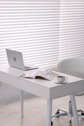 Photo of Open trendy magazine, laptop and coffee on white table indoors