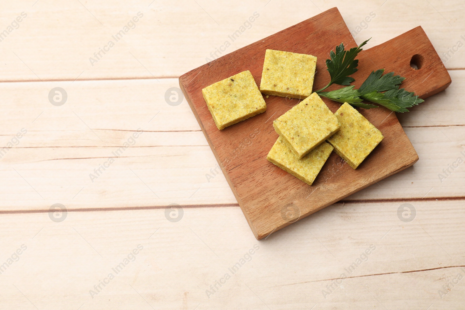 Photo of Aromatic bouillon cubes and parsley on wooden table, top view. Space for text