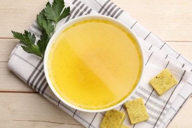 Photo of Aromatic bouillon cubes, broth and parsley on wooden table, flat lay