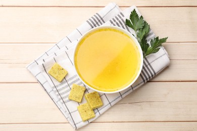 Photo of Aromatic bouillon cubes, broth and parsley on wooden table, flat lay
