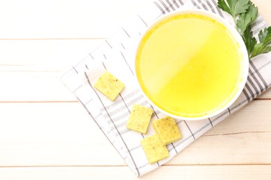 Photo of Aromatic bouillon cubes, broth and parsley on wooden table, flat lay. Space for text