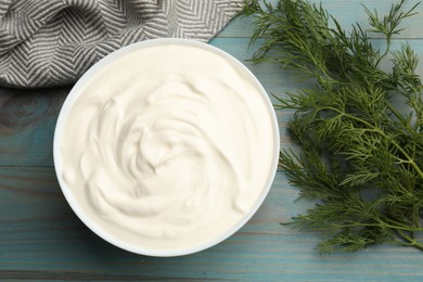 Photo of Tasty sour cream with dill on blue wooden table, top view