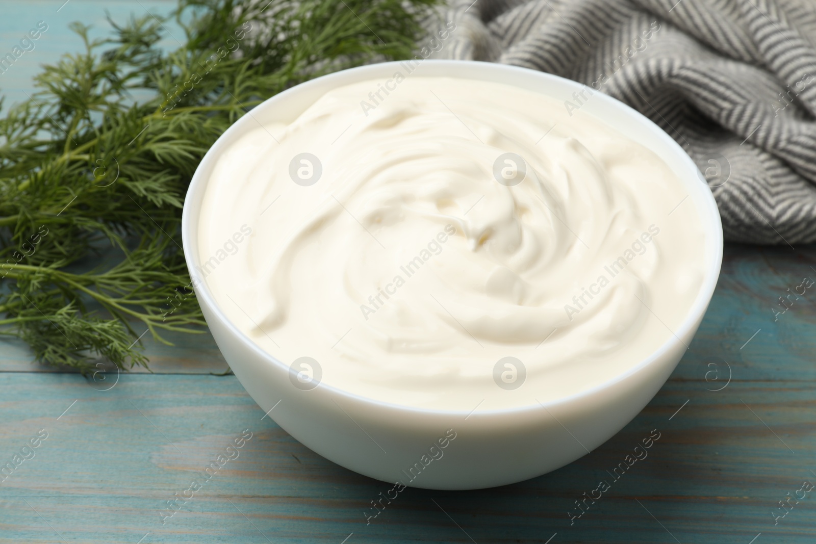 Tasty sour cream with dill on blue wooden table, closeup Photo of Tasty sour cream with dill on blue wooden table, closeup
