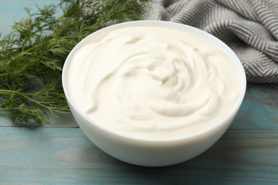 Photo of Tasty sour cream with dill on blue wooden table, closeup