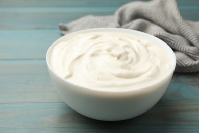 Photo of Tasty sour cream on blue wooden table, closeup
