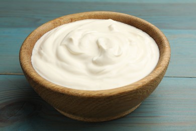 Photo of Tasty sour cream on blue wooden table, closeup