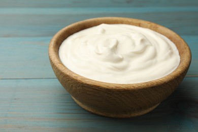 Photo of Tasty sour cream on blue wooden table, closeup