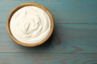 Photo of Tasty sour cream on blue wooden table, top view. Space for text