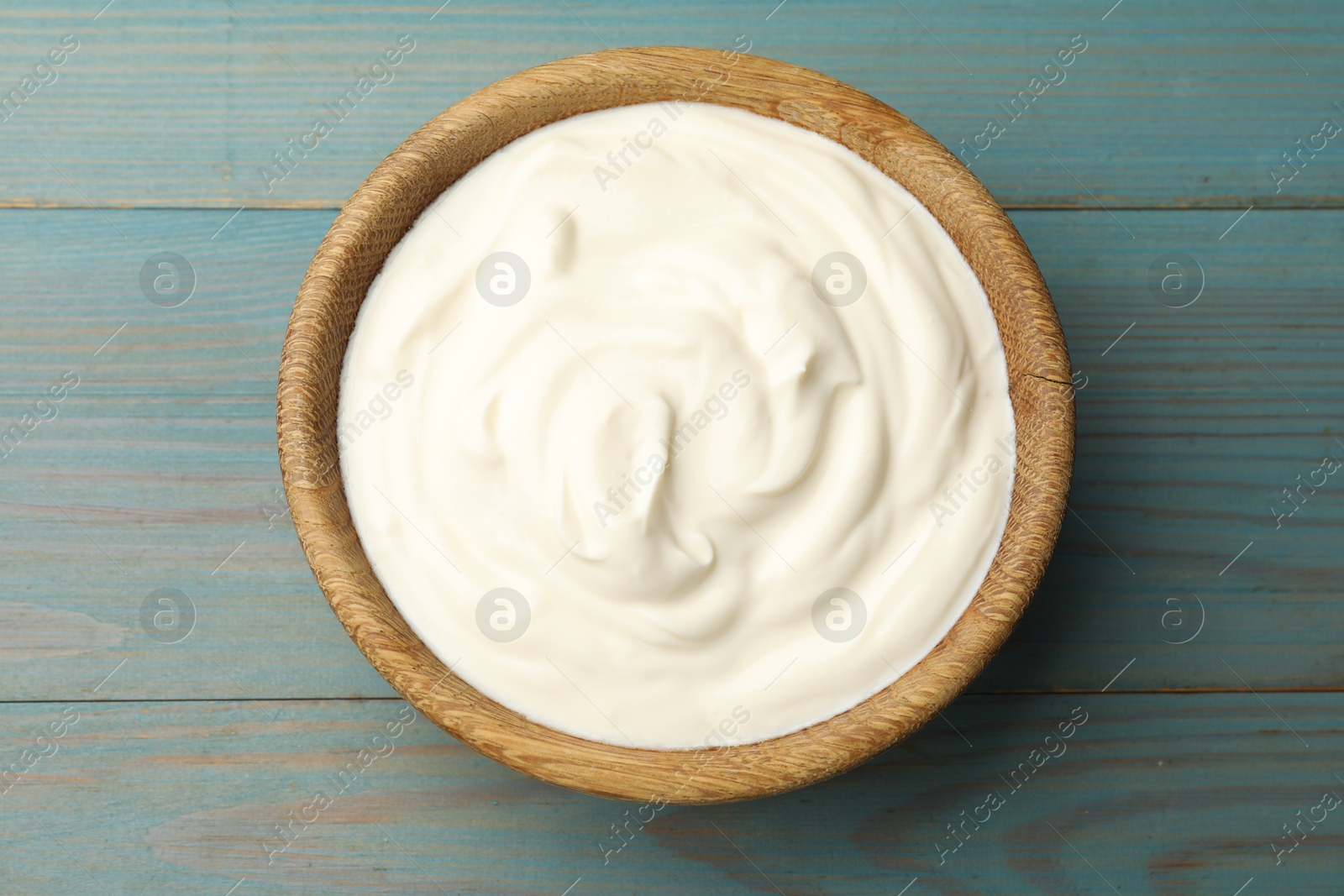 Photo of Tasty sour cream on blue wooden table, top view