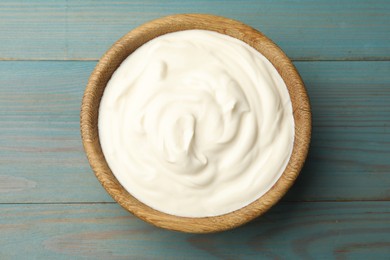 Photo of Tasty sour cream on blue wooden table, top view