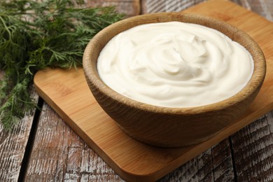 Photo of Tasty sour cream with dill on wooden table, closeup