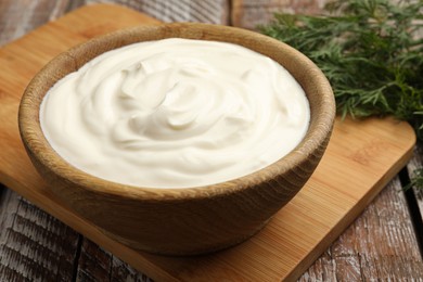 Photo of Tasty sour cream with dill on wooden table, closeup