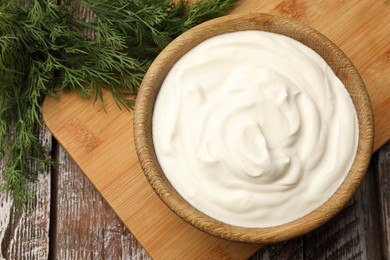 Photo of Tasty sour cream with dill on wooden table, top view