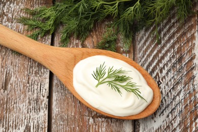 Photo of Tasty sour cream with dill on wooden table, top view