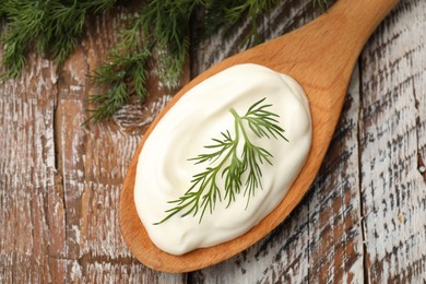 Photo of Tasty sour cream with dill on wooden table, top view