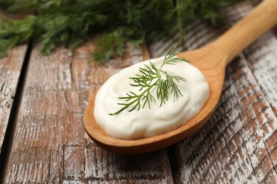 Photo of Tasty sour cream with dill on wooden table, closeup