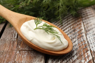 Photo of Tasty sour cream with dill on wooden table, closeup
