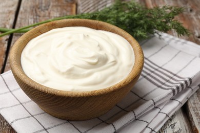 Photo of Tasty sour cream with dill on wooden table, closeup