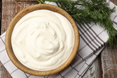 Photo of Tasty sour cream with dill on wooden table, flat lay