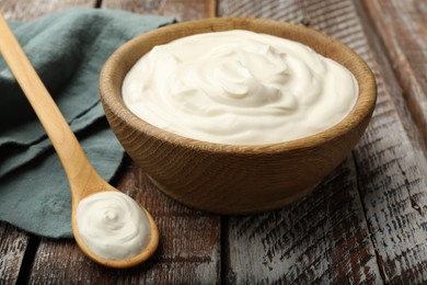 Photo of Tasty sour cream on wooden table, closeup