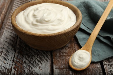 Photo of Tasty sour cream on wooden table, closeup