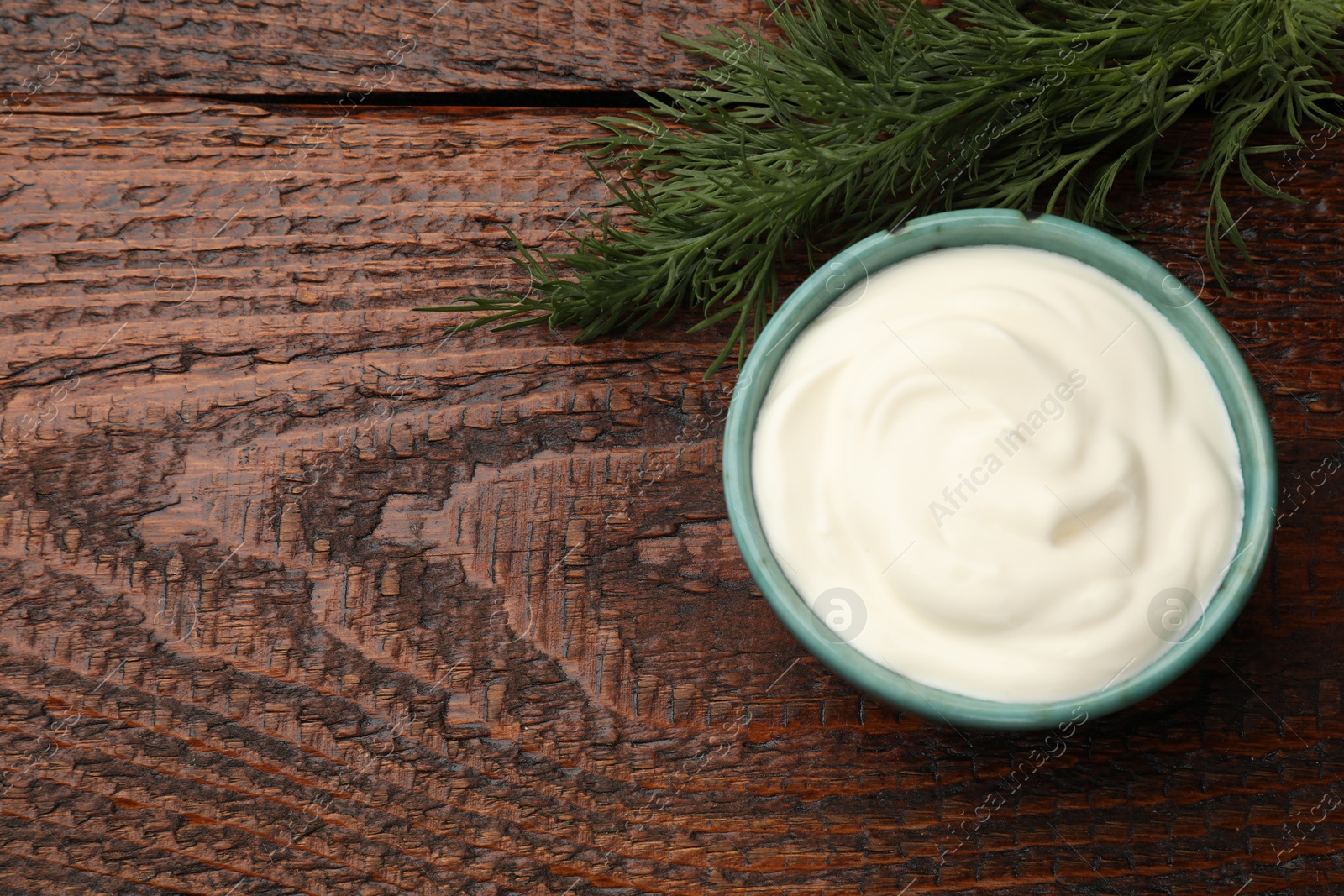Tasty sour cream with dill on wooden table, top view. Space for text Photo of Tasty sour cream with dill on wooden table, top view. Space for text
