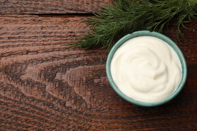 Photo of Tasty sour cream with dill on wooden table, top view. Space for text
