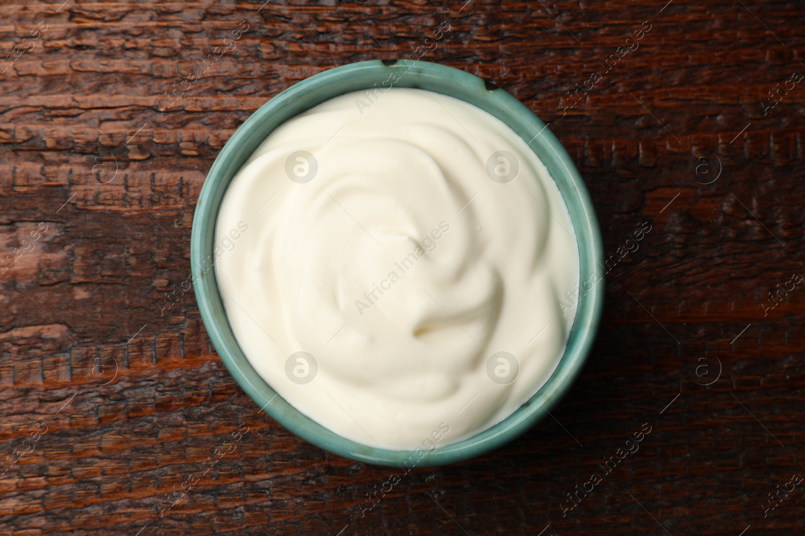 Photo of Tasty sour cream on wooden table, top view