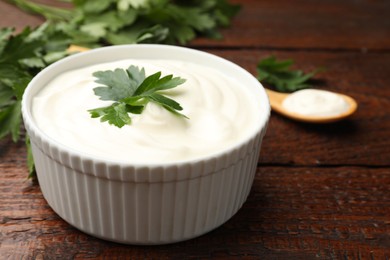Photo of Tasty sour cream with parsley on wooden table, closeup