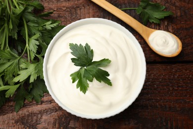 Photo of Tasty sour cream with parsley on wooden table, flat lay