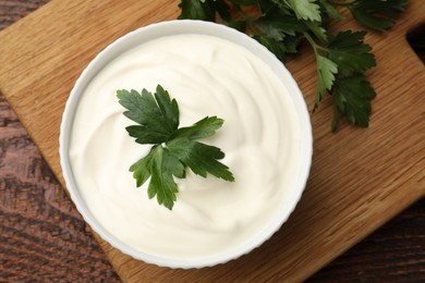 Photo of Tasty sour cream with parsley on wooden table, flat lay