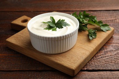 Photo of Tasty sour cream with parsley on wooden table