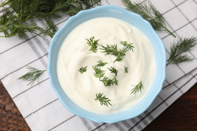 Photo of Tasty sour cream with dill on wooden table, flat lay