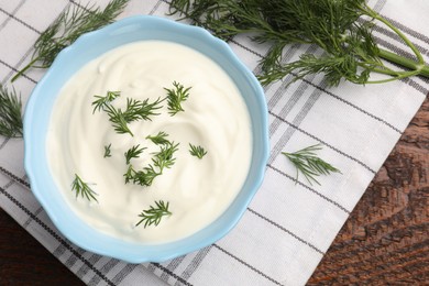 Photo of Tasty sour cream with dill on wooden table, flat lay