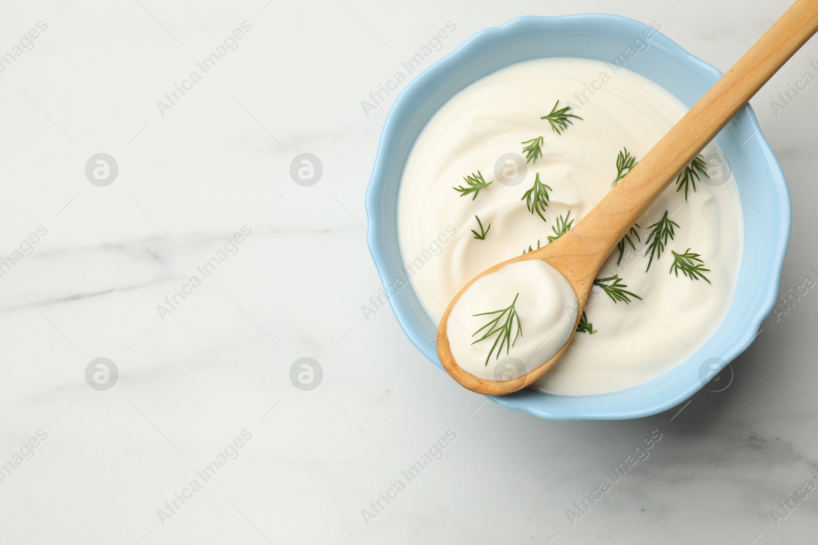 Tasty sour cream with dill on white table, top view. Space for text Photo of Tasty sour cream with dill on white table, top view. Space for text