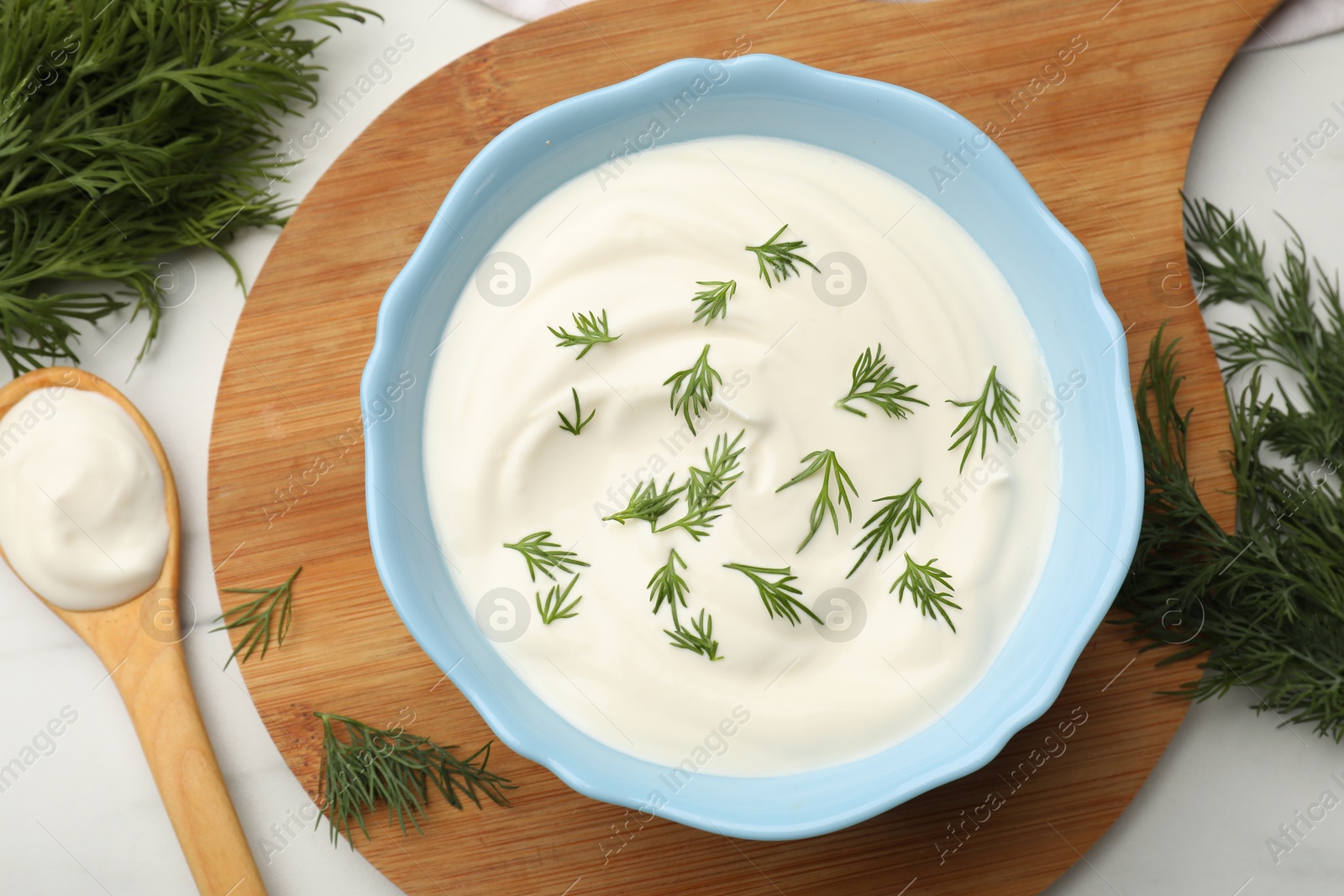Tasty sour cream and dill on white table, flat lay Photo of Tasty sour cream and dill on white table, flat lay