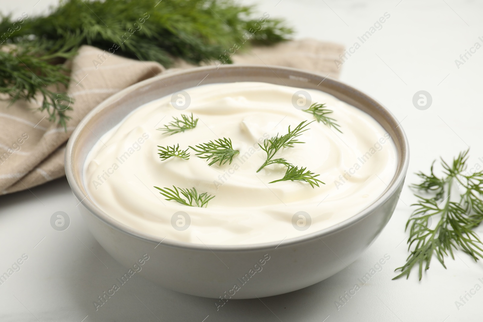 Tasty sour cream with dill on white table, closeup Photo of Tasty sour cream with dill on white table, closeup