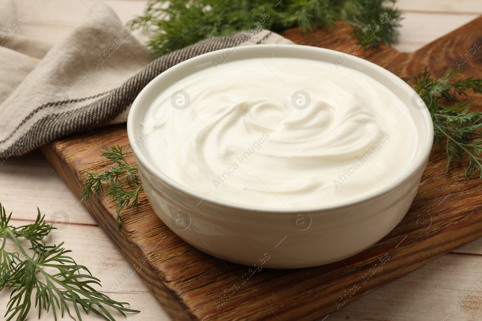 Tasty sour cream and dill on white wooden table, closeup Photo of Tasty sour cream and dill on white wooden table, closeup