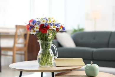Photo of Beautiful wildflowers in vase and book on wooden table at home. Space for text