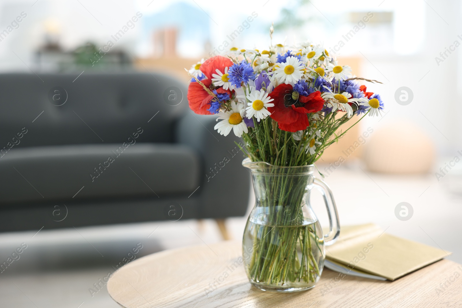 Photo of Beautiful wildflowers in vase and book on wooden table at home. Space for text